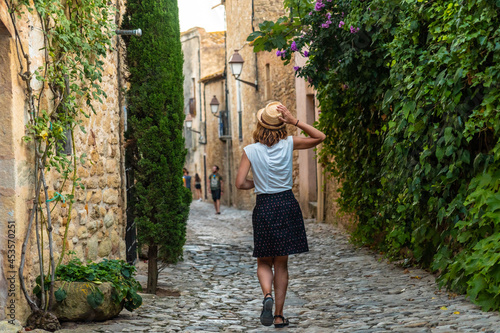 A tourist girl walking through the streets of Peratallada medieval town, historic center, Girona on the Costa Brava of Catalonia in the Mediterranean photo