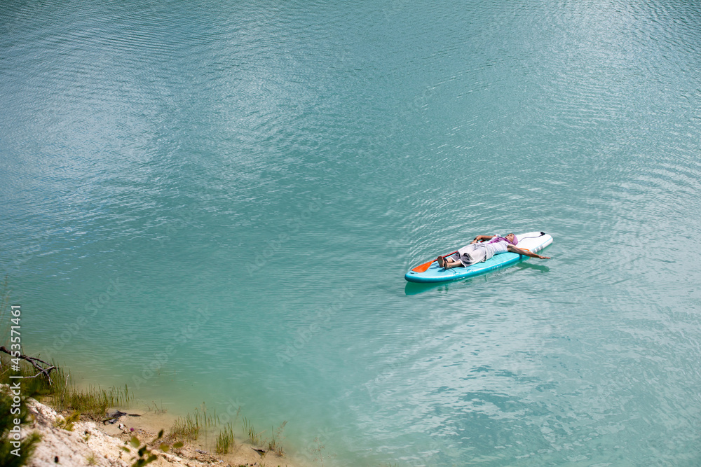 The girl is sunbathing on a sapa on a pond with turquoise water The girl is sunbathing on a sapa on a pond with turquoise water