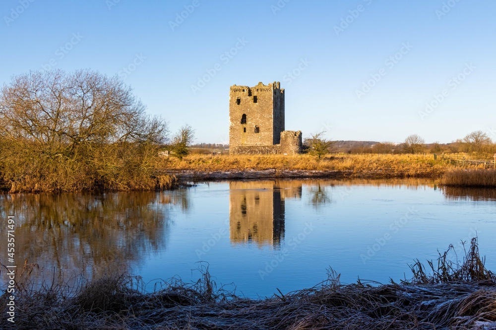 Threave Castle reflecting on the River Dee in the winter sun and ground frost