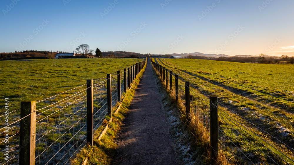 A fenced trail through agricultural land in the Scottish countryside in winter