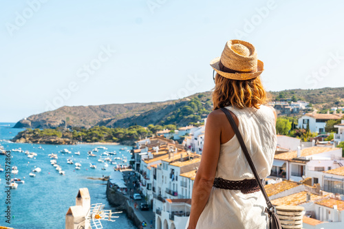 A young woman on vacation looking at the city of Cadaques from a viewpoint, Costa Brava of Catalonia, Gerona, Mediterranean Sea. Spain photo