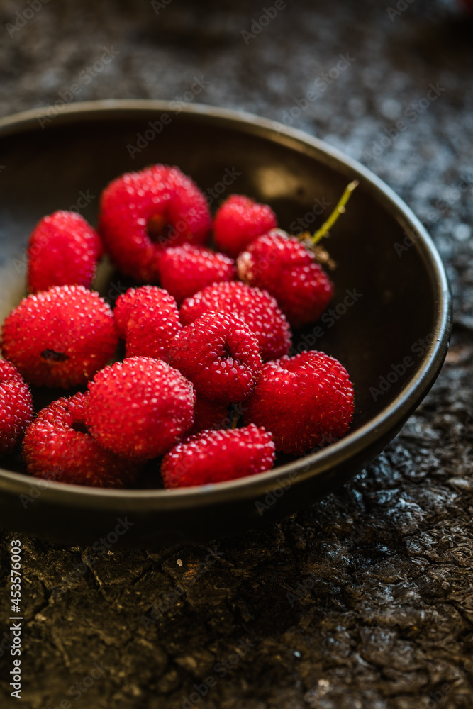 picking Tibetan raspberries in a black bowl on the background picking Tibetan raspberries in a black bowl on the background