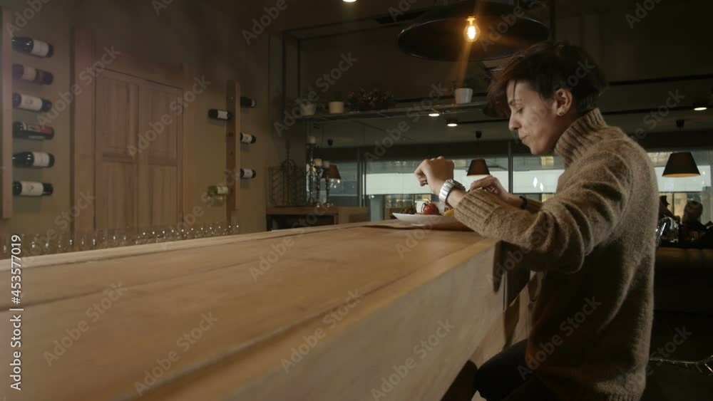 a girl with a short haircut appetizing eats sitting at the bar in the restaurant. High quality FullHD footage a girl with a short haircut appetizing eats sitting at the bar in the restaurant. High quality FullHD footage
