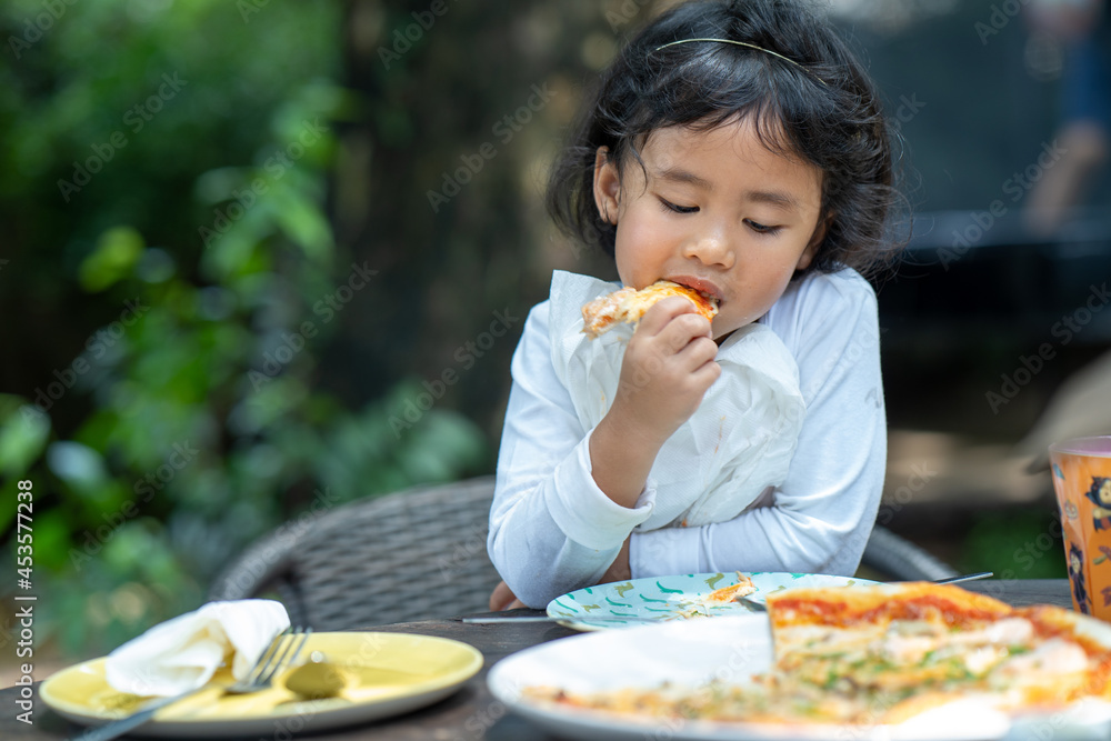 Little girl enjoy eating pizza outdoor. Little girl enjoy eating pizza outdoor.