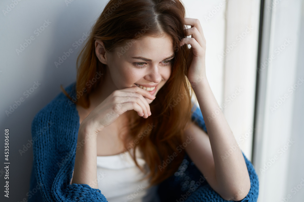 woman sitting on the windowsill with a blue plaid dreamy look woman sitting on the windowsill with a blue plaid dreamy look