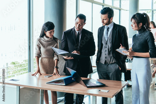 Two businessmen are negotiating a business together with their secretary at the office.