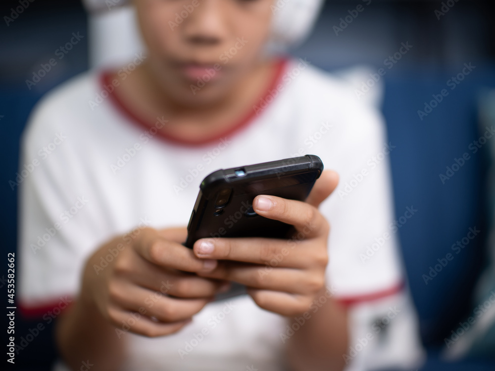 asian boy sit on sofa and using mobile phone in living room at home. asian boy sit on sofa and using mobile phone in living room at home.