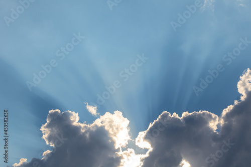 blue sky with clouds and diverging sun rays