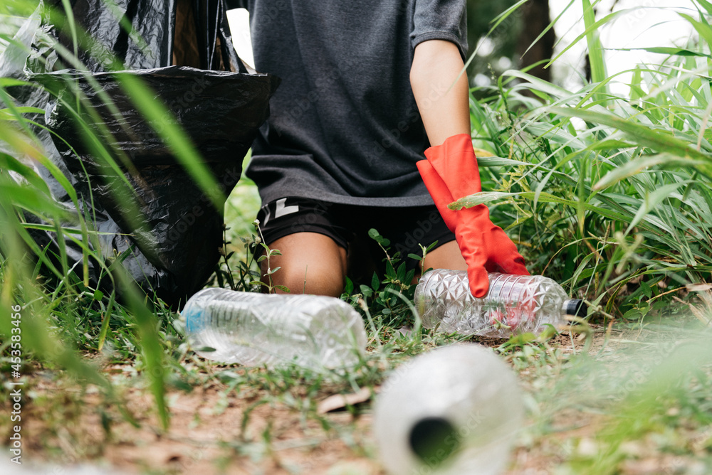 Fototapeta premium Boy man hand pick up plastic bottle in the forest. nature conservation and Environment concept.