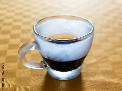 Iced cup of espresso on a table with orange tablecloth
