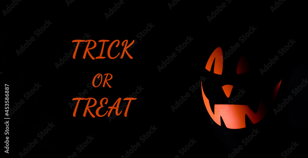 Scary black air balloon with orange face on a black background.Minimalistic Halloween background.Inscription TRICK OR TREAT. Scary black air balloon with orange face on a black background.Minimalistic Halloween background.Inscription TRICK OR TREAT.