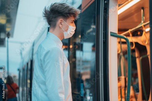 Adolescente joven rubio con mascarilla en la estaci  n de tren accediendo al interior