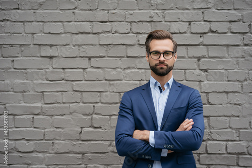 Portrait of handsome pensive businessman with arms crossed looking at camera, copy space