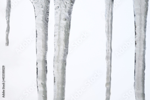 Icicles hanging on the roof. Winter nature abstract art. Physical phenomenon  solid form of water.