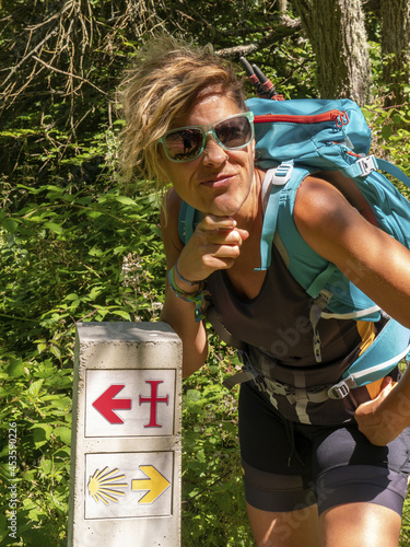 Closeup shot of a young confused hiker woman standing near a direction sign photo