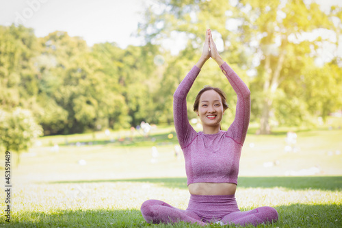Young Asian woman doing yoga fitness exercises in the nature park, Exercise for health or warm-up body, fresh air, or Oxygen in the green tree in the park in sunlight.