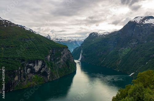 Beautiful Fjord Geirangerfjord with blue water, grey clouds and white snow picks view from Ornesvingen viewing point in Norway in summertime photo