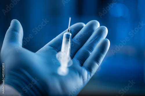 The hand of a scientist or doctor holds a bottle and syringe of serum drug for injections