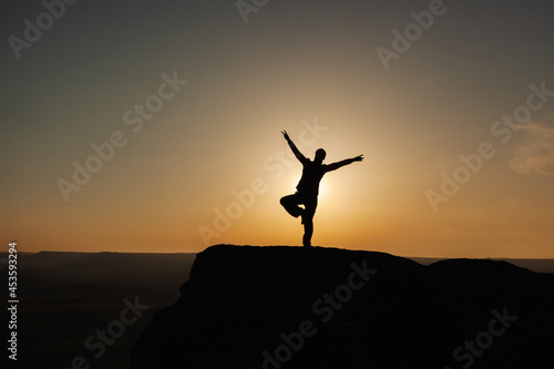 Silhouette of a man in the mountains against the background of the rising sun. The concept of freedom © Alernon77