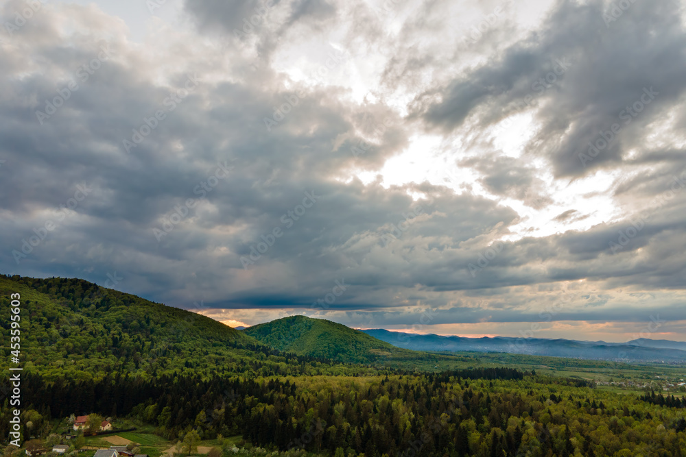 Fototapeta premium Aerial view of dark mountain hills covered with green mixed pine and lush forest in evening.