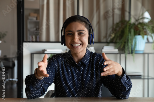 Head shot portrait of smiling Indian young businesswoman in headphones speaking and looking at camera  friendly employee worker consulting client online  involved in internet meeting  video call