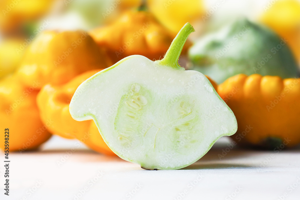 Half of fresh pattypan squash on white table. Pattypan squash or patisson, concept of vegetarian food. Green, orange and white squash as background Half of fresh pattypan squash on white table. Pattypan squash or patisson, concept of vegetarian food. Green, orange and white squash as background