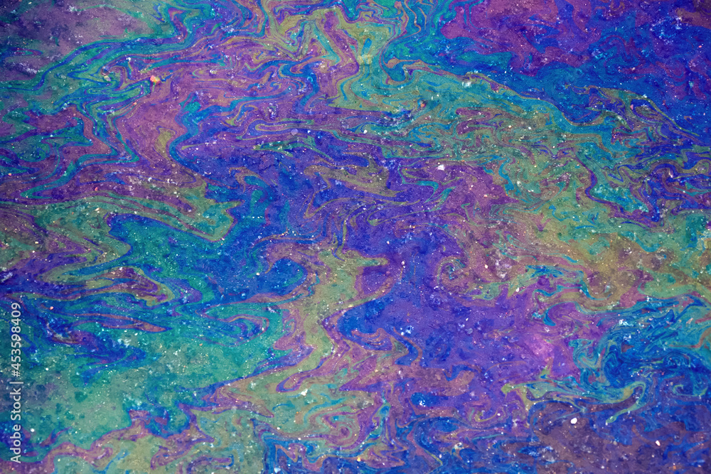 Oil stain on water, color gasoline fuel spots as texture or background. environmental pollution concept. Iridescent stains of gasoline, top view