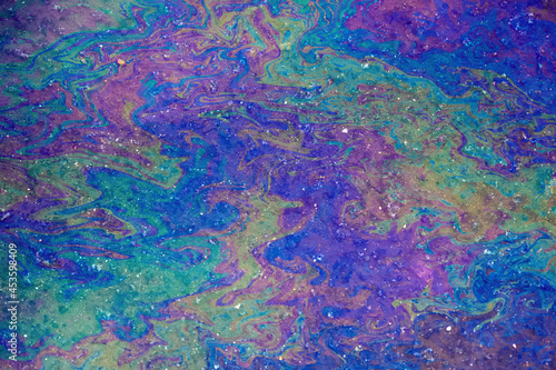 Oil stain on water, color gasoline fuel spots as texture or background. environmental pollution concept. Iridescent stains of gasoline, top view