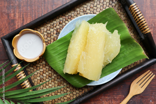 Boiled cassava or tapioca in syrup served with coconut milk - Thai dessert served in bamboo tray of the wood table