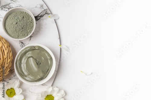Two bowls with blue cosmetic clay powder and wet on marble on white background