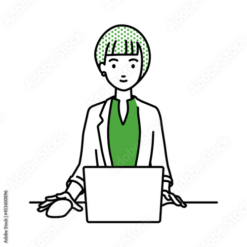 デスクで座ってPCを使っているジャケットの女性