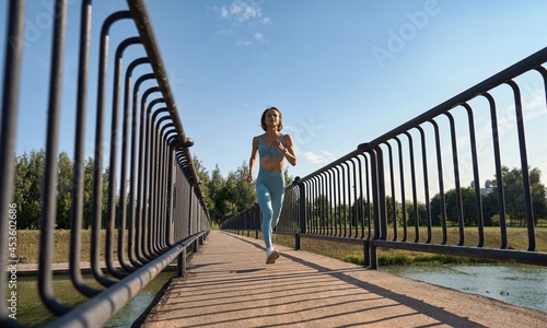 Beautiful female jogger running in the morning across bridge