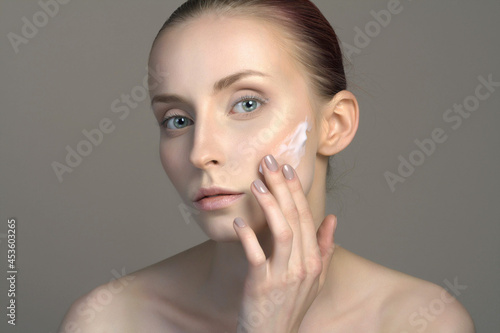 young woman girl applying cream on the face. beautiful model girl without make-up
