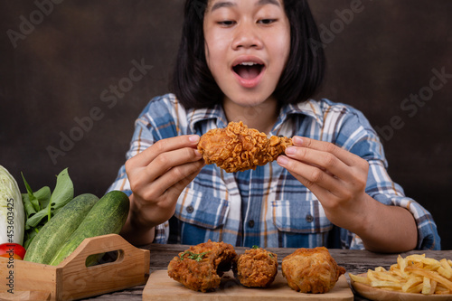 young girl eating fried chicken on a wooden chopping board
