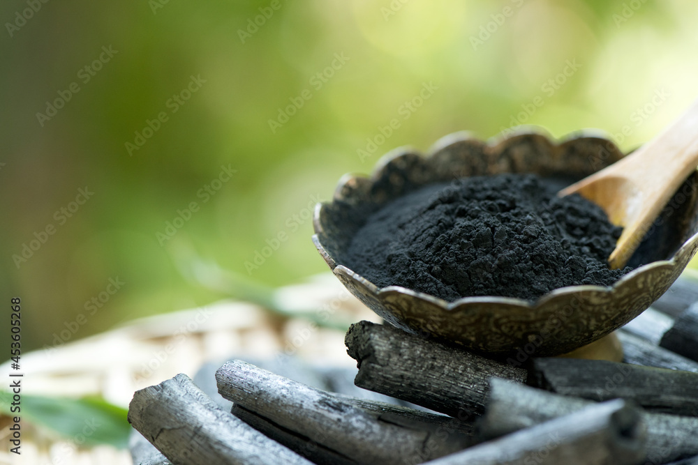 Obraz premium Bamboo charcoal ,green leaves and powder isolated on nature background.