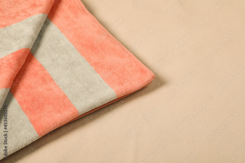 Fototapeta premium Striped soft beach towel on sand, closeup