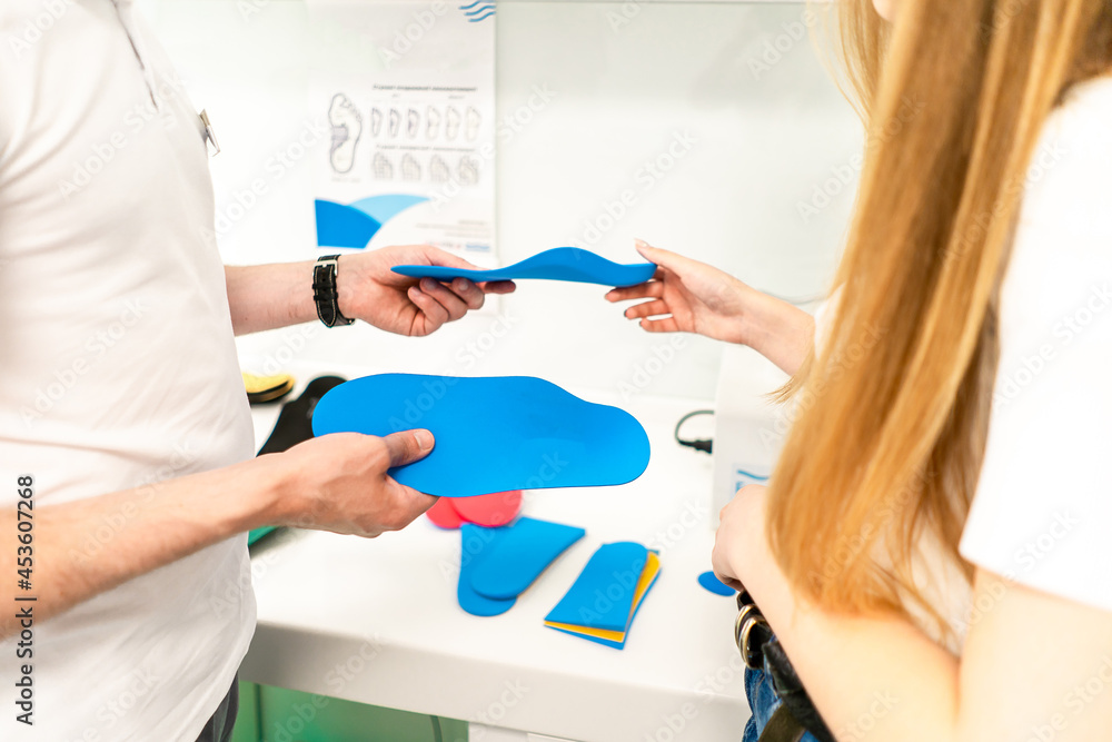 Orthopedic insole. The orthopedist works with the patient. Orthopedic clinic. Choice of insoles in an orthopedic clinic. The orthopedist offers the insole to the patient Foot care Orthopedic insole. The orthopedist works with the patient. Orthopedic clinic. Choice of insoles in an orthopedic clinic. The orthopedist offers the insole to the patient Foot care