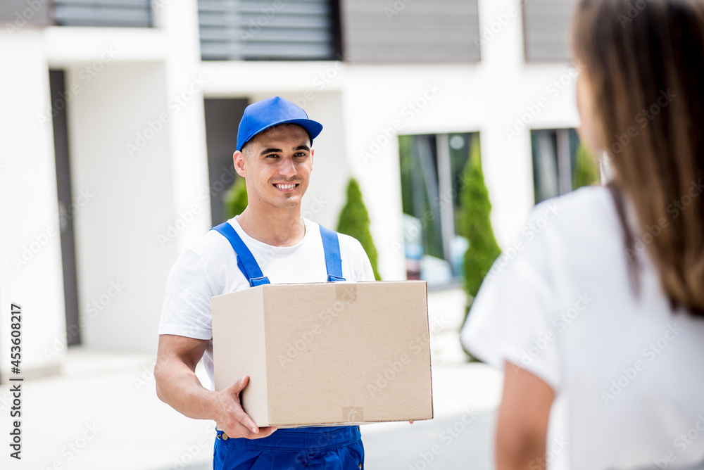 Young courier delivering goods to a young woman at home