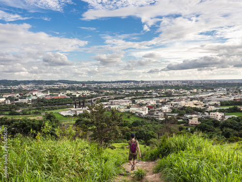 hiker and view of city from the beautiful mountain. Blue sky and green meadow.