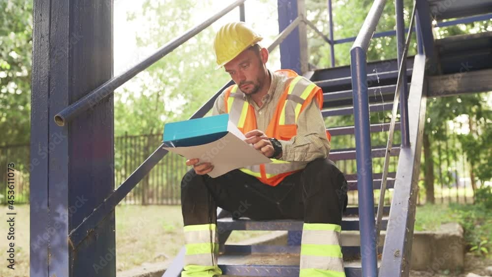 Architect Sitting On Stairs Looking Blueprint, analyzing building structure problems. Architect Sitting On Stairs Looking Blueprint, analyzing building structure problems.