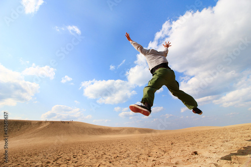 日本・鳥取砂丘でジャンプする男性の後ろ姿