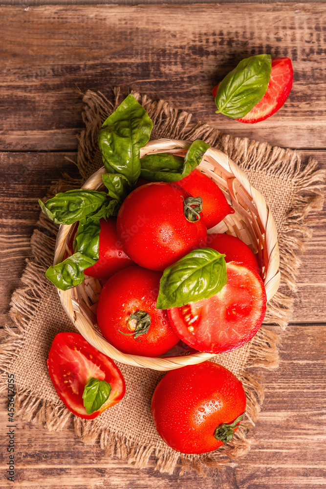 Ripe red tomatoes with fresh basil in a wicker basket Ripe red tomatoes with fresh basil in a wicker basket