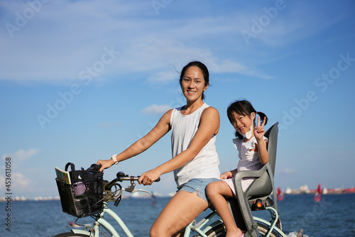 Asian Chinese Mother and daugther cycling outdoors with COVID mask