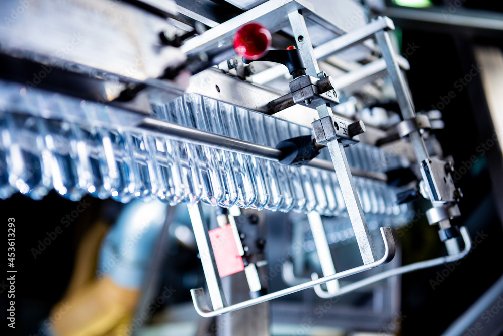 Automatic filling machine pours water into plastic PET bottles at modern beverage plant. Automatic filling machine pours water into plastic PET bottles at modern beverage plant.