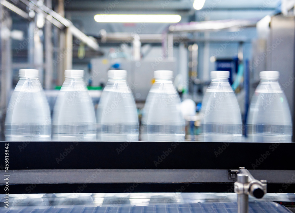 Conveyor belt with bottles of drinking water at a modern beverage plant. Conveyor belt with bottles of drinking water at a modern beverage plant.