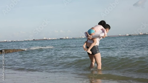 4K Slow mo asian chinese Father piggy back young daughter at the beach