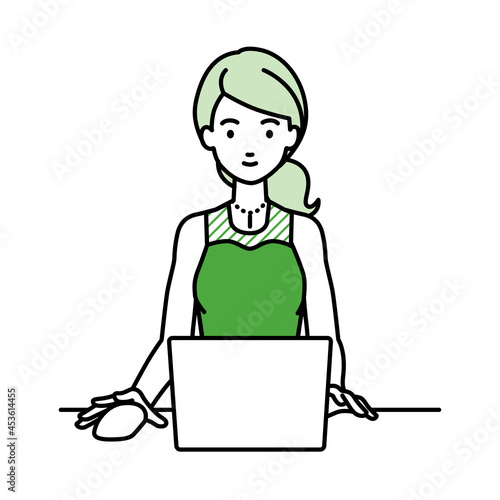 デスクで座ってPCを使っているドレスの女性