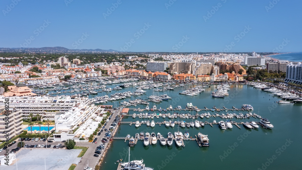 A view from the sky of the tourist Portuguese town of Vilamoura, with Yachts and sailboats moored in the port on the dock.