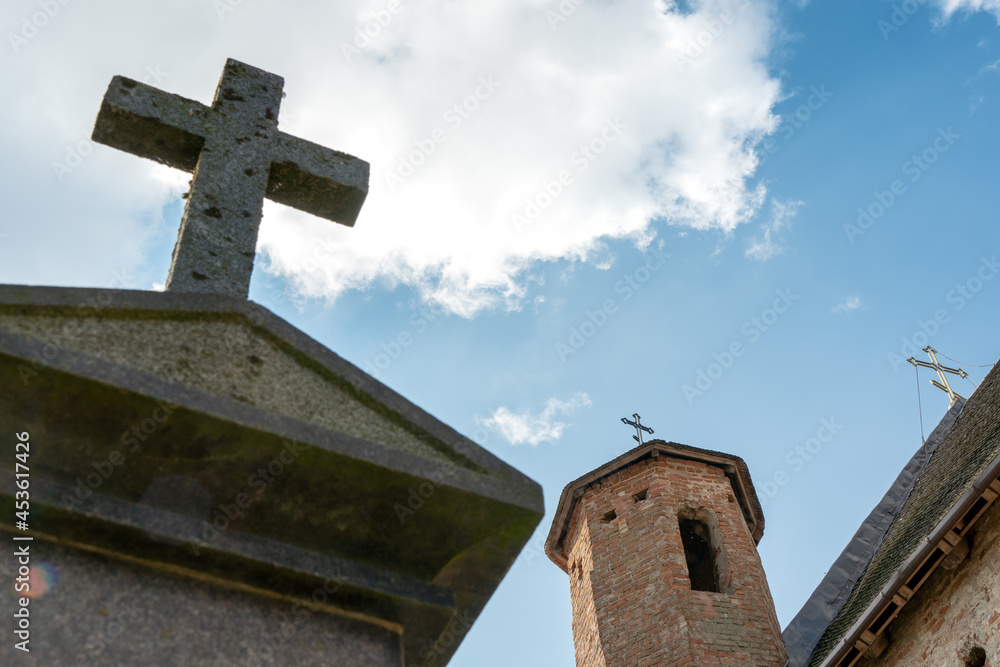 A beautiful old fortress church made of red brick against a blue sky background. A large stone cross on the background of the brick wall of the old castle. A beautiful old fortress church made of red brick against a blue sky background. A large stone cross on the background of the brick wall of the old castle.