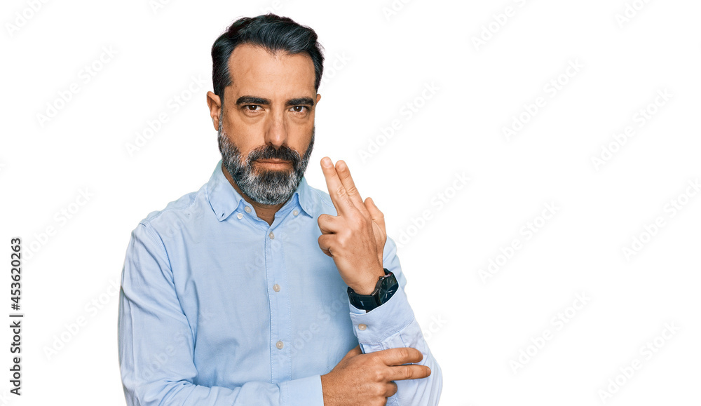 Middle aged man with beard wearing business shirt holding symbolic gun with hand gesture, playing killing shooting weapons, angry face Middle aged man with beard wearing business shirt holding symbolic gun with hand gesture, playing killing shooting weapons, angry face
